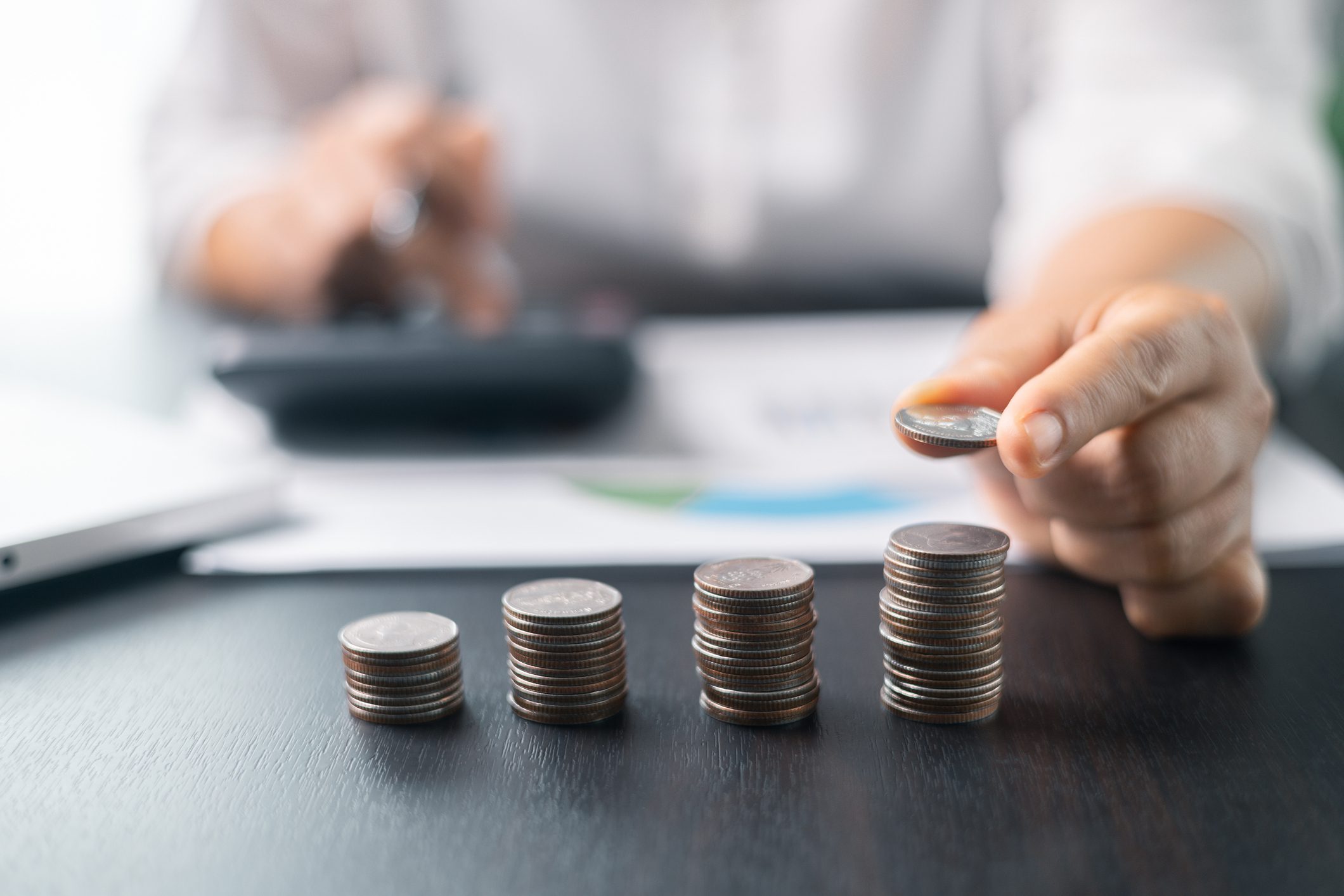 Stacked coins with person calculating